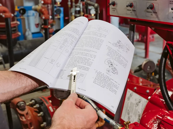 Técnico consultando el manual del motor en la sala de bombas