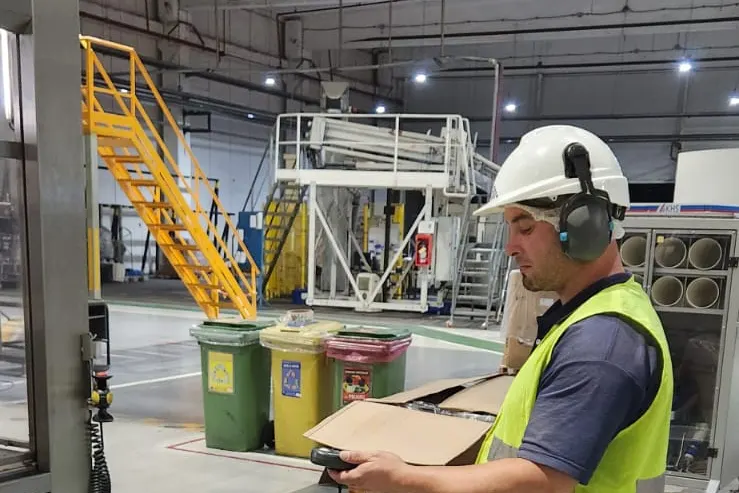 Técnico con protección auditiva registrando una medición en una planta industrial
